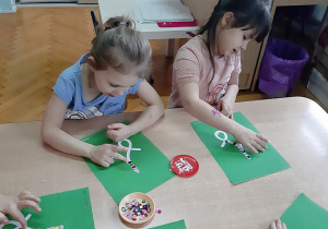 Dzieci wyklejają wzór do Rysowanych piosenek przy użyciu kolorowych cekinów.